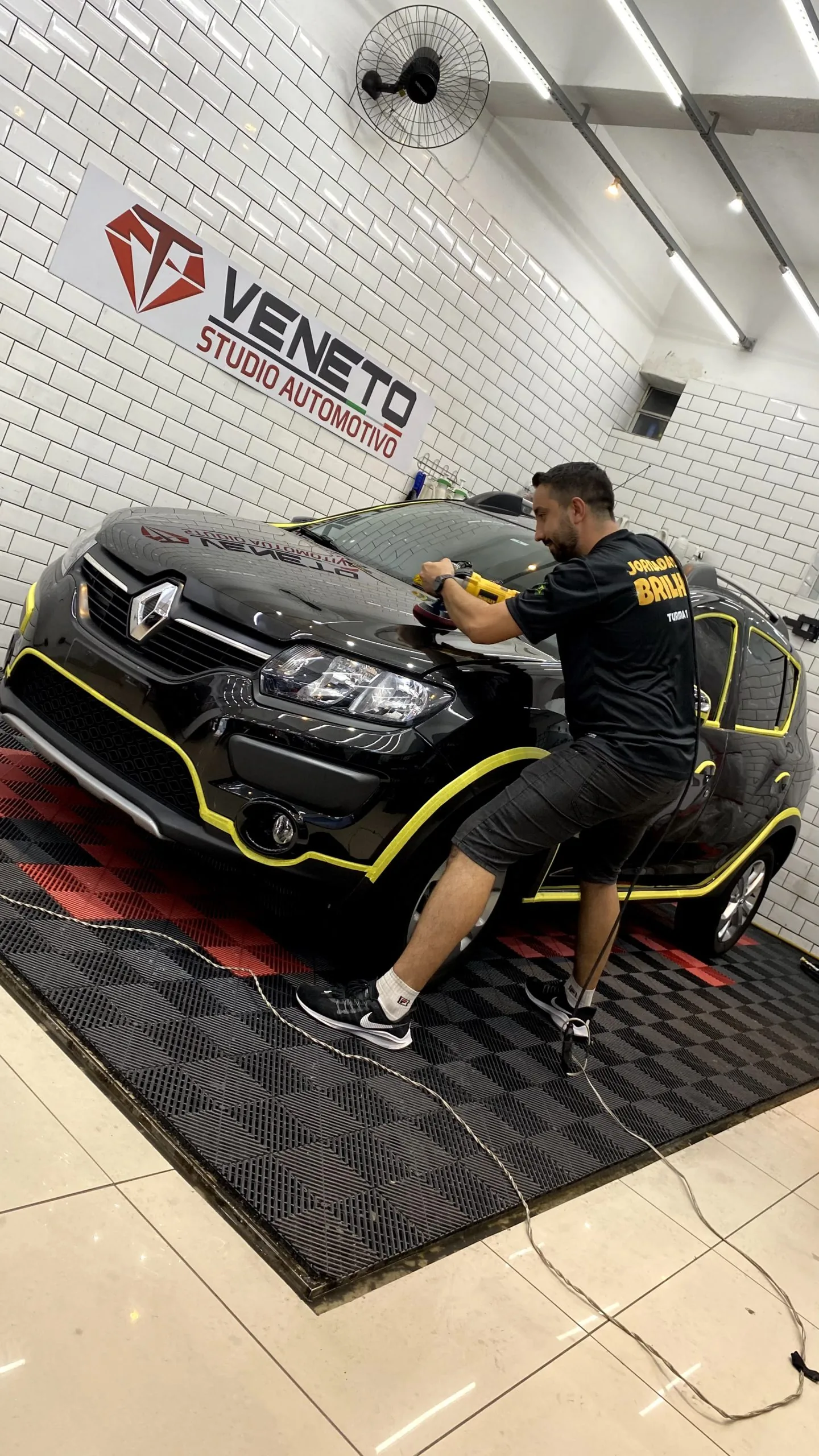 Profissional realiza polimento técnico na pintura de um carro.
